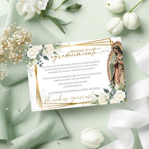 Pode incluir: Um cartão de agradecimento em espanhol com uma moldura geométrica dourada, apresentando uma ilustração da Virgem Maria. O cartão é decorado com rosas brancas e vegetação, em um fundo verde suave com fitas e flores brancas.