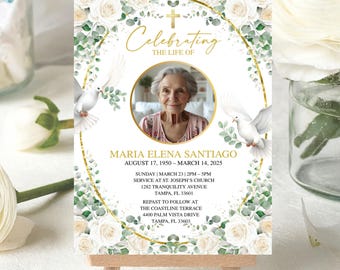 May include: A memorial card on a wooden easel, featuring a photo of Maria Elena Santiago. The card is decorated with white roses, green foliage, and doves. Gold accents frame the photo and text, which includes dates and service details.