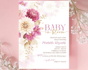 May include: A baby shower invitation with a floral design. The invitation says "Baby in Bloom" and includes the name "Mathilda Reynolds". The invitation also includes the date, time, and location of the shower.
