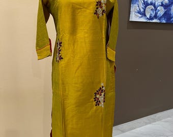 Puede incluir: Una kurta de manga larga de color amarillo mostaza con bordados florales en tonos rojos, blancos y morados. La kurta tiene un cuello redondo y una abertura lateral.