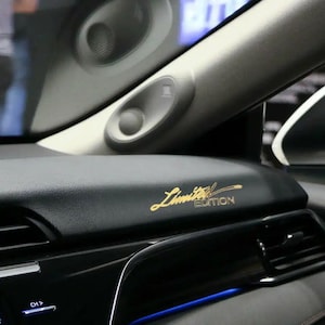 May include: Close-up of a black car interior with a gold "Limited Edition" inscription on the dashboard.