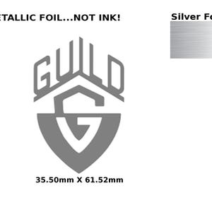 May include: A silver foil sticker with the text "GUILD" in a stylized font. The sticker features a shield with a stylized "G" inside. The text "METALLIC FOIL...NOT INK!" appears above the sticker. The text "Silver Foil" appears in the upper right corner of the image. The sticker measures 35.50mm x 61.52mm.