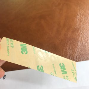 Puede incluir: Un rollo de cinta adhesiva transparente con texto verde que dice "3M 467MP 200MP Adhesive" y "3M 67MP Adhesive".