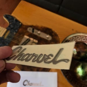 May include: A silver Charvel guitar decal on a white background.