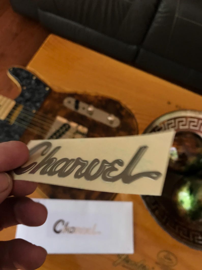 May include: A silver Charvel guitar decal on a white background.