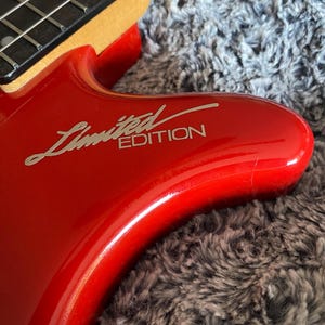 May include: Close-up of a red electric bass guitar with a silver "Limited Edition" inscription on the body.