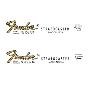 May include: A gold Fender Stratocaster guitar decal with the text "Fender", "STRATOCASTER", "SERIAL NUMBER N3153734", "MADE IN U.S.A.", and "ORIGINAL Contour Body Pat Pend".