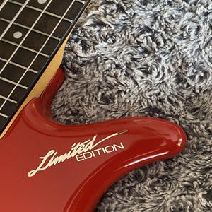 May include: A red electric bass guitar with a black fretboard and a gold "Limited Edition" inscription on the body.