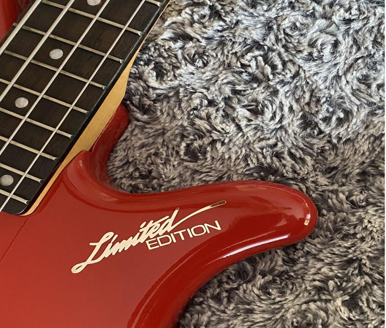 May include: A red electric bass guitar with a black fretboard and a gold "Limited Edition" inscription on the body.