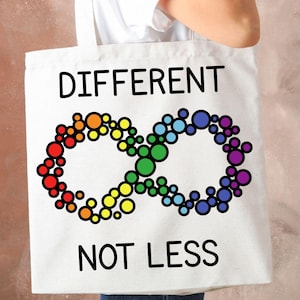 Könnte beinhalten: Weiße Tragetasche mit den Worten "DIFFERENT NOT LESS" in Schwarz. Die Tasche zeigt ein farbenfrohes Unendlichkeitszeichen aus regenbogenfarbenen Kreisen, das das Bewusstsein für Autismus darstellt.