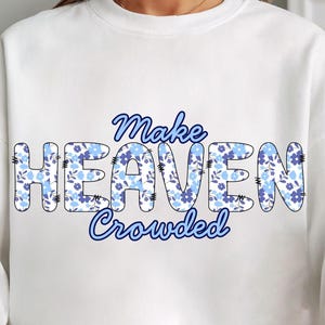 Könnte beinhalten: Weißes Sweatshirt mit dem Schriftzug "Make Heaven Crowded" in Blau. Das Wort "HEAVEN" ist mit einem blauen Blumenmuster gefüllt. Ein lässiges, bequemes Oberteil für den Alltag.