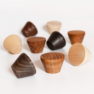 Op de afbeelding: Een verzameling van negen houten kastknoppen in verschillende tinten bruin en natuurlijk hout. De knoppen hebben een conische of afgeronde vorm, met zichtbare houtnerf. De kleuren variëren van lichtbeige tot donkerbruin.
