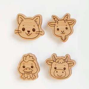 May include: Four wooden animal-shaped cutouts: a cat, goat, duckling, and cow. Each cutout features a detailed outline and facial features, with a natural wood grain finish. The cat has whiskers, the goat has horns, the duckling has a beak, and the cow has horns.
