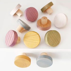 Peut inclure: Ensemble de boutons de meubles en bois de différentes couleurs : rose, jaune, vert et tons naturels. Les boutons ont un design rond et plat avec une base cylindrique, idéal pour ajouter une touche de couleur à tout meuble.