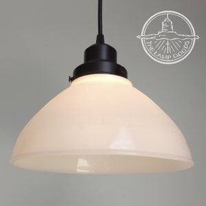 May include: A white glass pendant light shade with a black metal fixture. The shade has a textured, frosted finish and a rounded, dome shape.