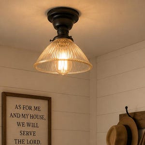 May include: A ceiling-mounted light fixture with a black base and a ribbed glass shade. The entryway features a wooden bench with two wicker baskets, a framed sign reading "AS FOR ME AND MY HOUSE, WE WILL SERVE THE LORD. JOSHUA 24:15", and a coat rack.