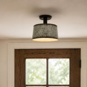 May include: A semi-flush mount ceiling light fixture featuring a cylindrical, galvanized metal shade with a weathered, textured gray finish and a black metal canopy, providing downward illumination in a residential entryway setting.