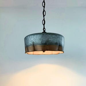 May include: A hanging pendant light with a galvanized metal shade. The shade has a scalloped edge and a two-tone finish, with a silver-gray top and a copper-colored bottom. The light hangs from a black chain.