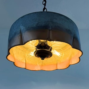 May include: A hanging pendant light with a galvanized metal shade and a copper-colored trim. The interior features exposed light bulbs, casting a warm glow. The fixture is suspended from a chain, offering a vintage or industrial aesthetic.