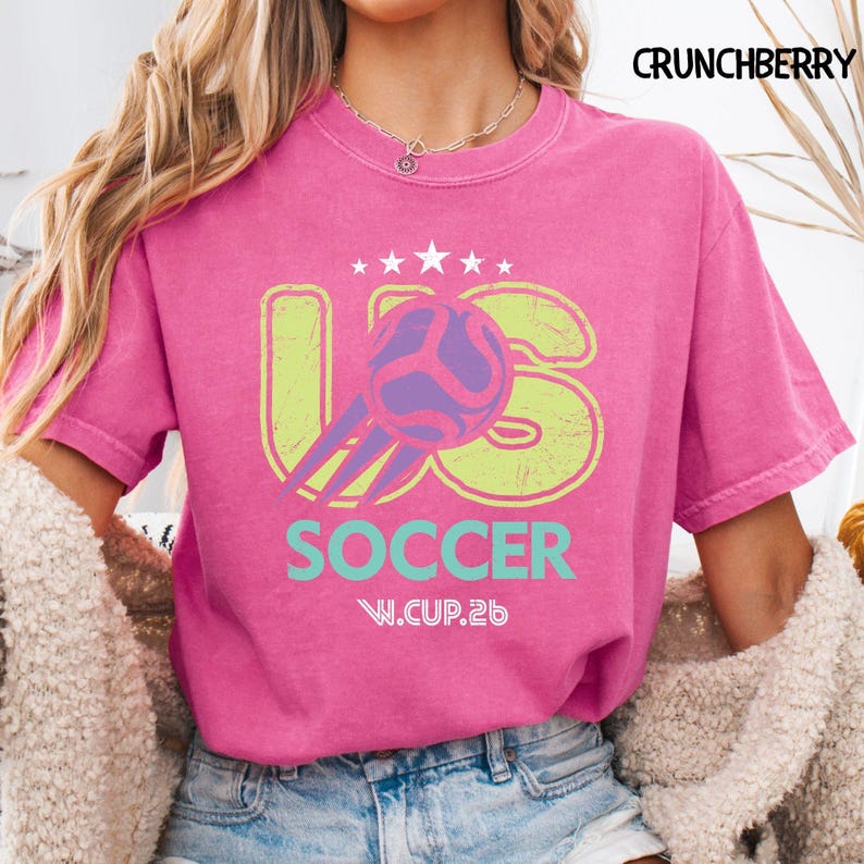 Model wearing a bright crunchberry pink Comfort Colors shirt featuring a retro soccer tournament logo with a weathered finish.