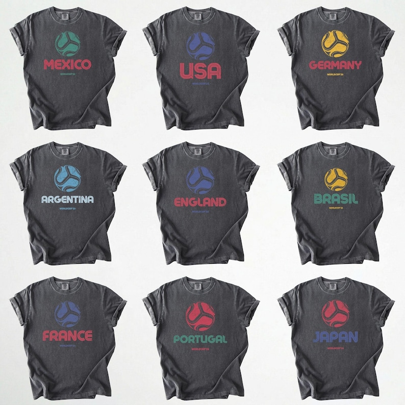 May include: Nine dark grey t-shirts, each displaying a country name and a soccer ball design. The shirts feature the names Mexico, USA, Germany, Argentina, England, Brazil, France, Portugal, and Japan, each with a unique ball colour.