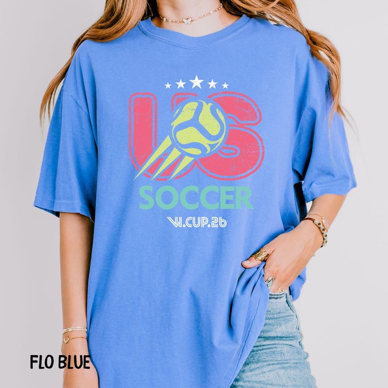 A model in a flo blue oversized t-shirt featuring the US Soccer graphic, paired with denim jeans for a casual look.
