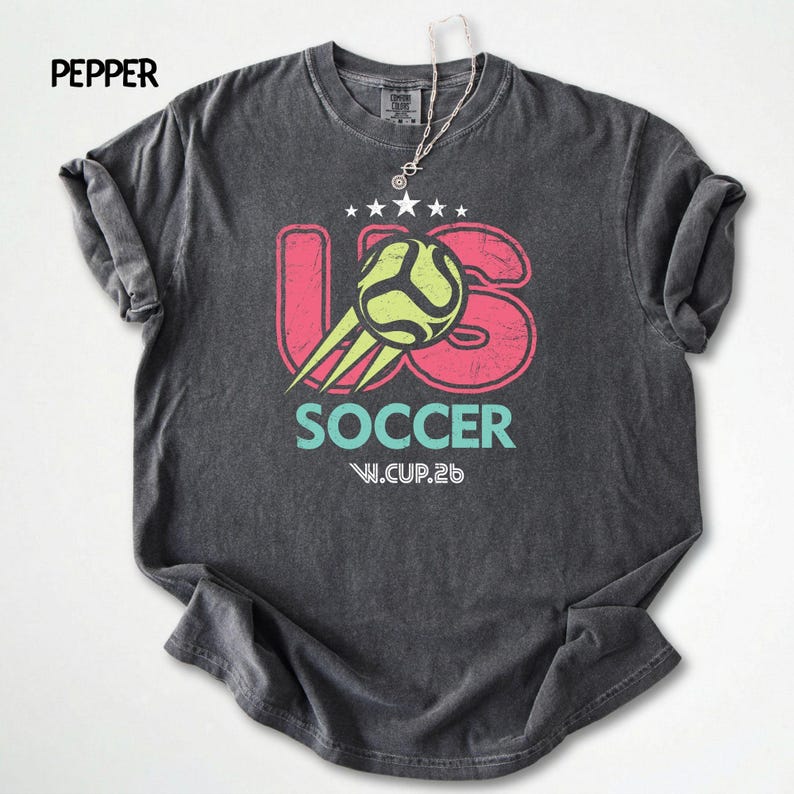 Flat lay view of a pepper dark gray Comfort Colors 1717 t-shirt with a vintage-effect soccer ball and stars print.