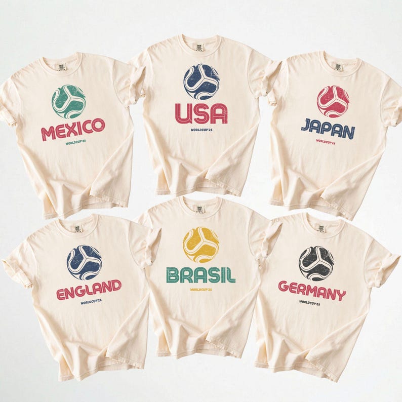 May include: Six cream-coloured t-shirts with soccer ball graphics and country names: Mexico, USA, Japan, England, Brazil, and Germany. Each shirt has a distressed print of a soccer ball and the text "WORLDCUP 24".