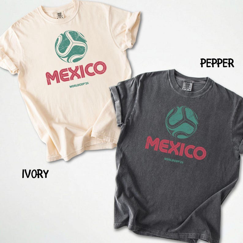 May include: Two t-shirts, one ivory and one pepper, with rolled sleeves. Each shirt features a soccer ball graphic above the word "MEXICO" in red, with "WORLDCUP26" below. The soccer ball is teal.
