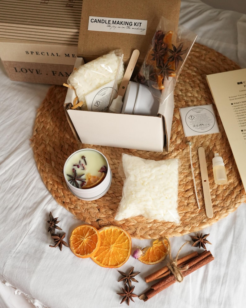 May include: Candle making kit with a white tin candle, dried orange slices, star anise, and cinnamon sticks. The kit includes wax, a small spatula, and a label that reads "Candle Making Kit".