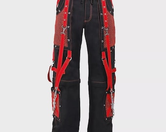 Op de afbeelding: Zwarte broek met rode details, waaronder rode banden, mesh panelen en kettingen. De broek heeft een taille met trekkoord en rode stiksels. Een uniek ontwerp voor alternatieve mode.
