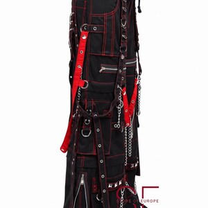 Puede incluir: Pantalones cargo negros con costuras rojas en contraste, m&uacute;ltiples bolsillos utilitarios, cremalleras de metal plateado, anillas en D y correas colgantes. Los pantalones incluyen cadenas de metal y el texto STORE OF EUROPE en la parte inferior.