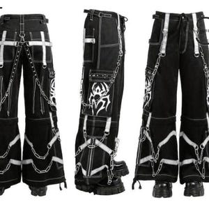 May include: Black cargo pants with white accents, chains, and decorative stitching. The pants feature multiple pockets, straps, and a flared leg design. The image shows the pants from multiple angles.