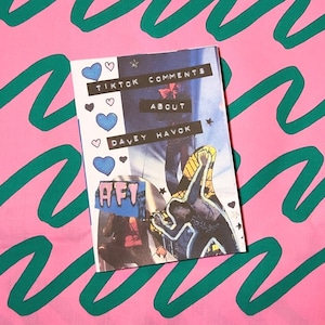 May include: A zine with the title "TikTok Comments About Davey Havok" is shown against a pink background with green wavy lines. The zine features blue hearts and the band's logo "AFI".