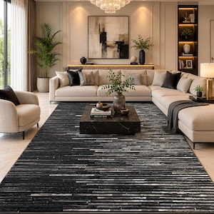 Puede incluir: Una alfombra rectangular con un patrón de rayas horizontales en tonos negro, carbón y blanco. La alfombra presenta un diseño lineal texturizado con longitudes variables de tonos oscuros y claros, creando una apariencia de capas en la superficie.
