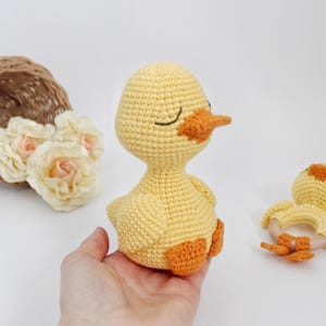 Puede incluir: Dos juguetes de pato amarillo de crochet. El pato m&aacute;s grande tiene una expresi&oacute;n de ojos cerrados y un pico naranja. El pato m&aacute;s peque&ntilde;o tiene un anillo de madera unido a su cuerpo.