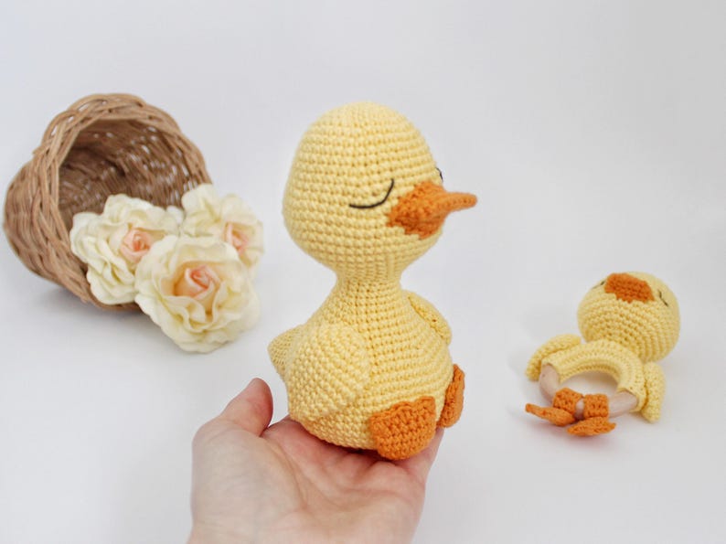 Puede incluir: Dos juguetes de pato amarillo de crochet. El pato m&aacute;s grande tiene una expresi&oacute;n de ojos cerrados y un pico naranja. El pato m&aacute;s peque&ntilde;o tiene un anillo de madera unido a su cuerpo.