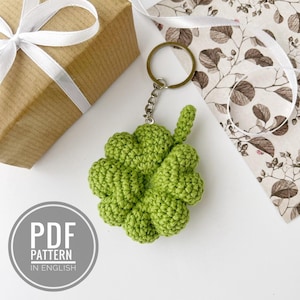 Puede incluir: Llavero de trébol de cuatro hojas tejido a crochet en verde con un anillo de metal plateado.  PDF PATTERN IN ENGLISH.