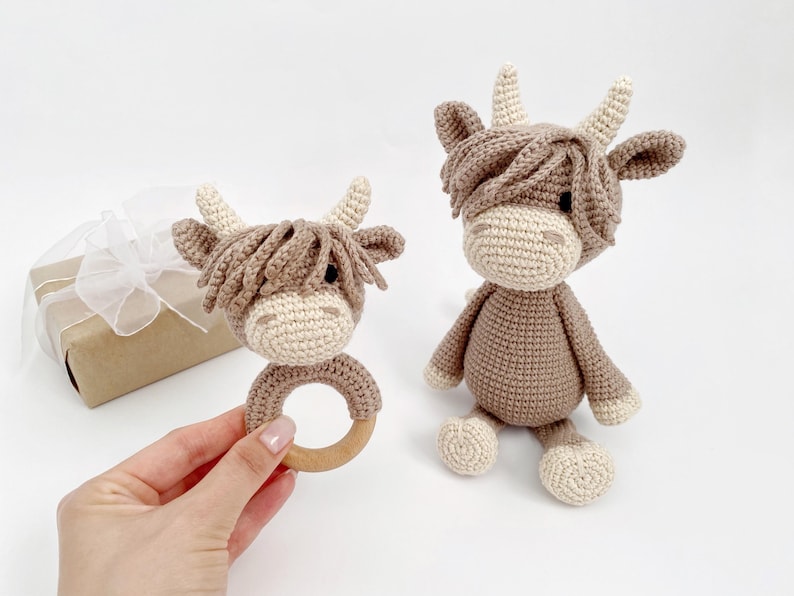 Puede incluir: Dos peluches de vaca Highland de crochet marr&oacute;n y blanco. Uno es un peluche m&aacute;s grande y el otro es un peluche m&aacute;s peque&ntilde;o unido a un anillo de madera.