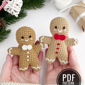 Può includere: Due figure di pan di zenzero all'uncinetto in filato color marrone chiaro con tratti del viso ricamati e dettagli bianchi o rossi. Una figura indossa un papillon e bottoni bianchi, l'altra un papillon e bottoni rossi. Testo: PDF PATTERN IN ENGLISH.