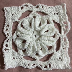 May include: White crocheted square with a large, detailed flower in the centre.