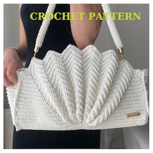 May include: White crochet handbag with a gold chain strap. The bag has a chevron pattern and a gold label with the word "CROCHET PATTERN" on it.