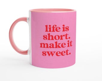 May include: Pink ceramic mug with a white interior and a red inscription that reads "life is short. make it sweet."