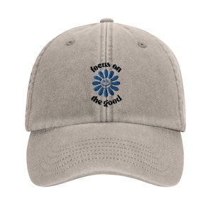 Peut inclure: Une casquette de baseball en coton gris avec une fleur bleue brodée et le texte "focus on the good".