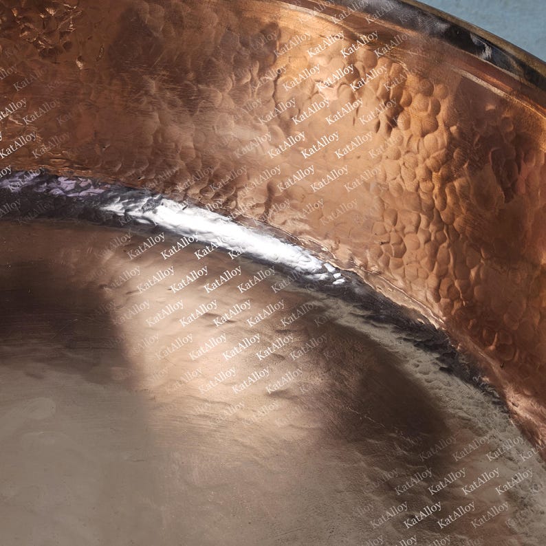 May include: A close-up of a copper bowl with a hammered texture. The bowl is shiny and reflects light.