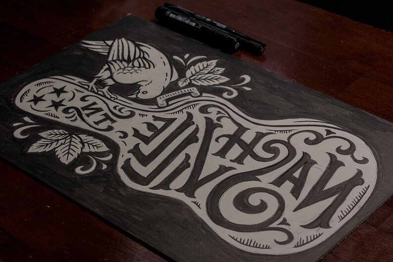 May include: A black and white illustration of a guitar with the words "The Wild" written on it. A bird is perched on top of the guitar.