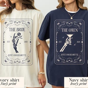 May include: Ivory and navy shirts with a graphic design for a bachelorette party. The ivory shirt has a navy print that says "THE BRIDE" with a skeleton hand holding a rose. The navy shirt has an ivory print that says "THE COVEN" with a skeleton hand holding a cocktail glass.