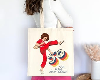 May include: A white canvas tote bag with a red and yellow illustration of a woman kicking a large number 50. The text "I Like To Kick, Stretch, And Kick!" is printed below the illustration.