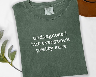 May include: A green t-shirt with the text "undiagnosed but everyone's pretty sure" printed in white.