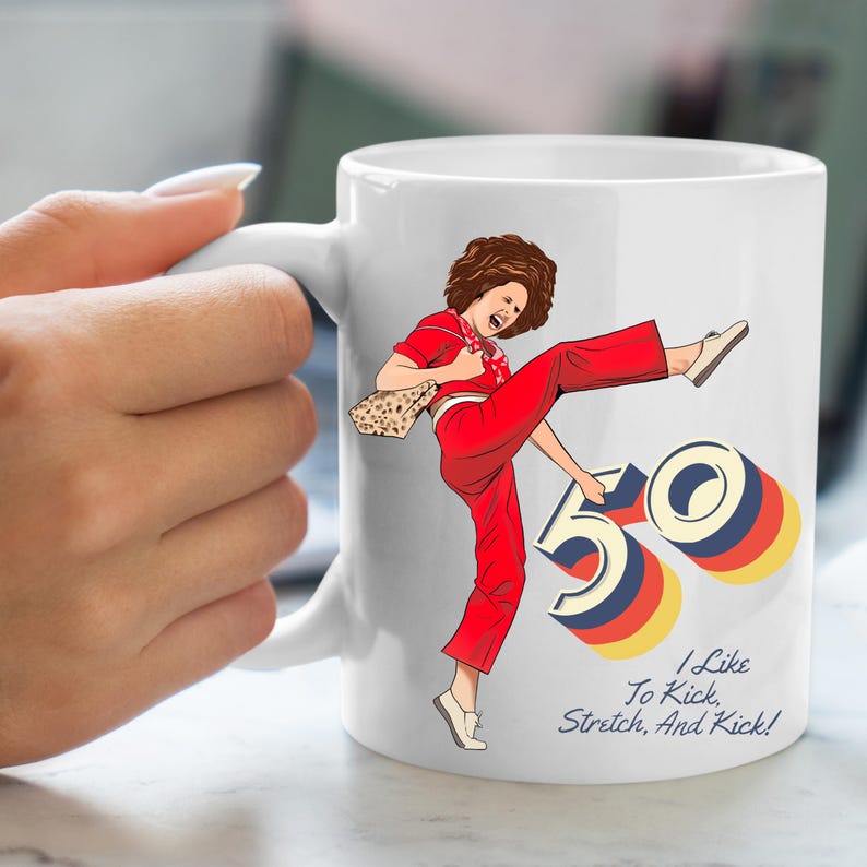 May include: White ceramic mug with a colorful illustration of a woman kicking a large number 50. The text "I Like To Kick, Stretch, And Kick!" is printed on the mug.